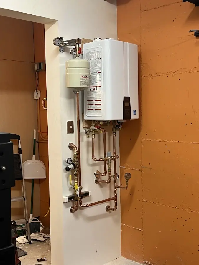 Plumbing technician inspecting water heater connections in Brandon